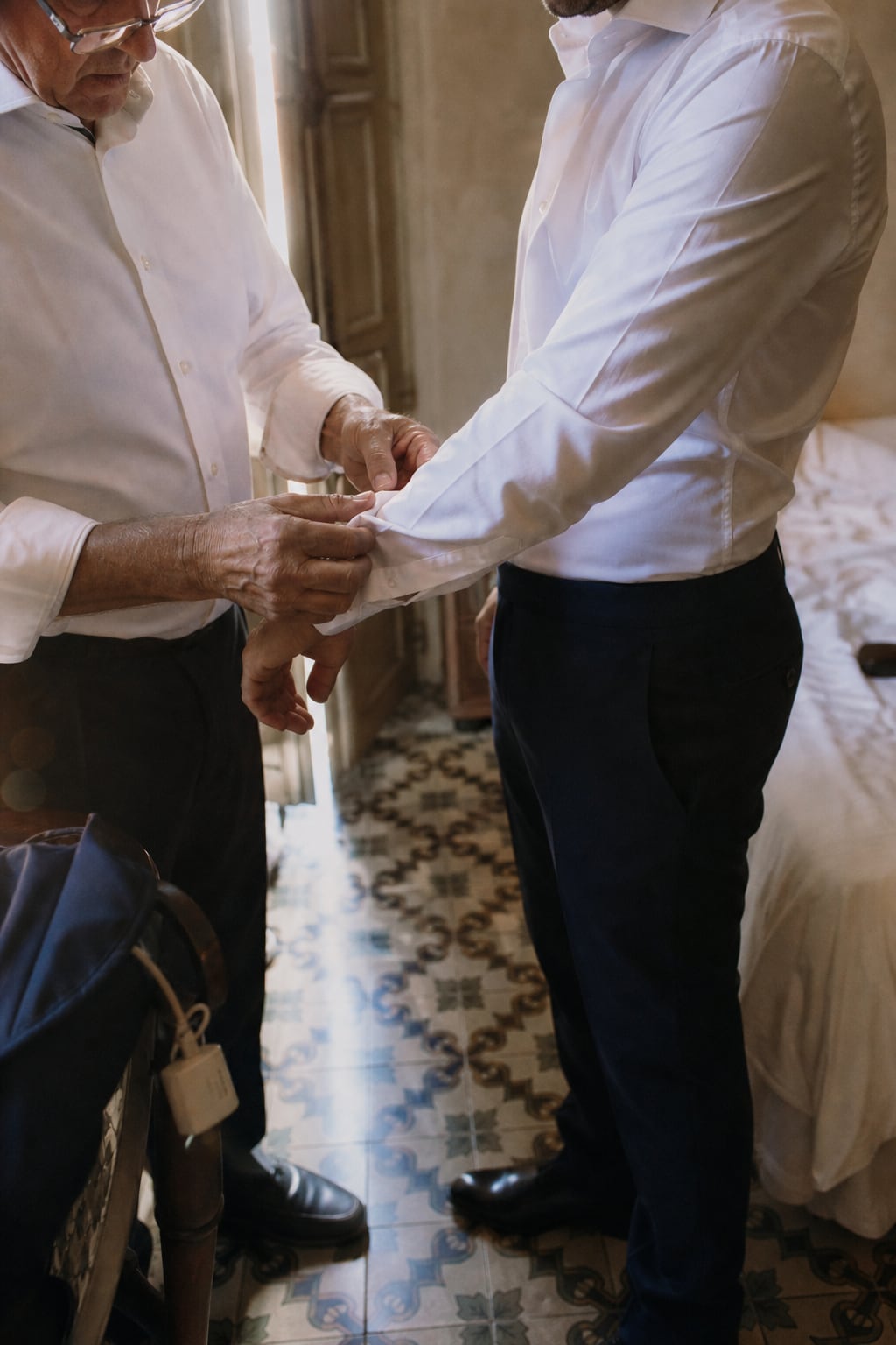 The groom's father helping with his cufflinks, on traditional Valencian tiles